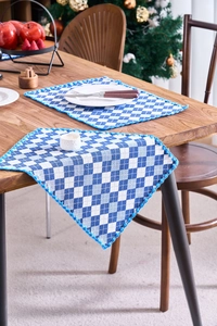 Blue and white gingham placemats with crochet lace edges on a wooden table setup