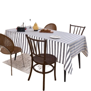 Modern blue and white striped linen tablecloth with lace edges on a wooden dining table