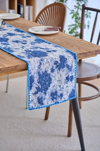 Detailed close-up of blue and white floral jacquard table runner with delicate lace trim