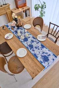 Detailed close-up of blue floral jacquard table runner with vintage fringe trim
