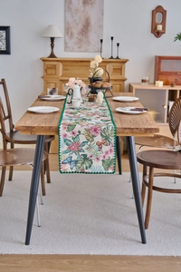Detail of floral butterfly jacquard table runner with textured weaving and green border