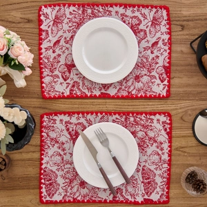 Macro detail of rectangle place mat with red butterfly embroidery and pom-pom trim edge