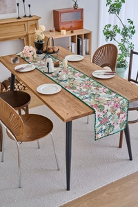 Detail of floral butterfly jacquard table runner with green wavy scalloped edges
