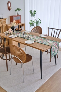 Close-up of tropical floral table runner with green lace edge on wooden dining table