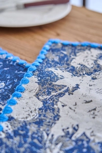 Close-up of jacquard navy blue table runner with intricate floral fringe detail