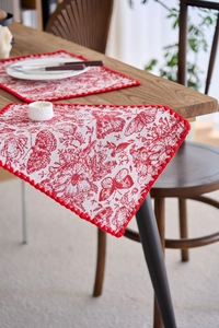 Detail view of red jacquard floral table mat with elegant butterfly embroidery and red borders
