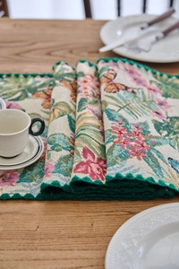 Close-up of jacquard floral table runner with butterfly motifs and green crochet edge