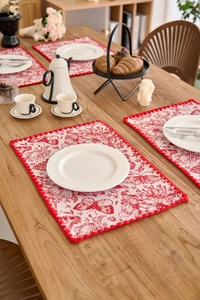 Detail of red butterfly jacquard table mat with pom-pom trim and floral embroidery