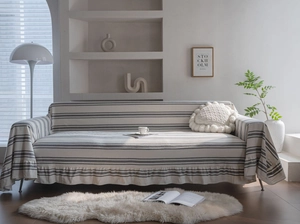 Detailed view of striped cotton sofa cover featuring elegant ruffled hem and soft texture