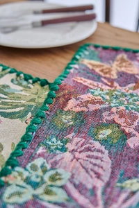 Detailed view of jacquard table runner with butterfly patterns and green pompom edge