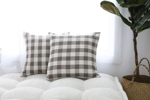 Close-up detail of two brown gingham checkered decorative throw pillow covers on a bench