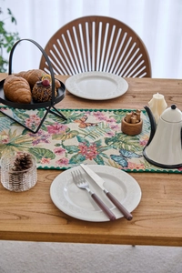 Close-up of jacquard table runner with butterfly and floral patterns on a wooden table