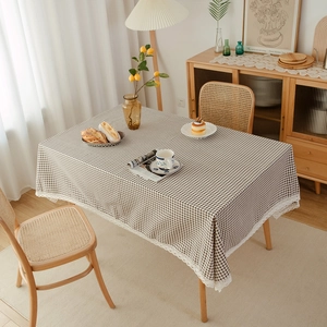 Close-up of brown plaid tablecloth with white lace edges on a wooden table setup