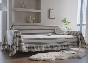 Detail of minimalist striped sofa cover with elegant ruffled edges in cream and grey