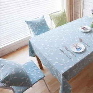 Detailed view of light blue cotton linen tablecloth and chair cushion with leaf prints