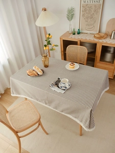 Detail shot of brown plaid tablecloth with delicate white lace trim on a wooden table