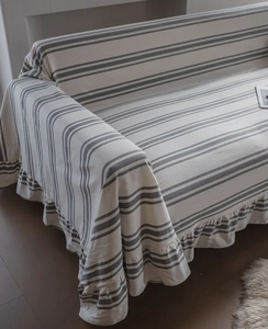 Detail of grey and beige striped sofa cover with elegant ruffle hem and fabric texture