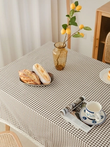 Close-up of brown checkered tablecloth with white lace trim and rustic picnic accessories