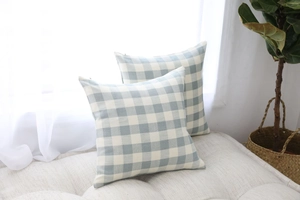 Detail view of blue and white checkered Nordic pillow covers on a minimalist sofa