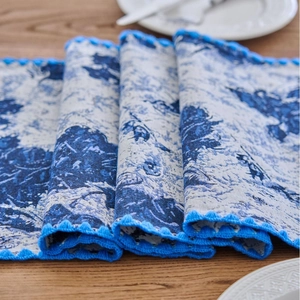 Navy blue jacquard table runner with white floral patterns on a light wooden table