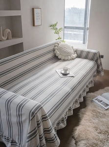 Detail of striped cotton sofa cover featuring elegant ruffled edges and a modern minimalist design