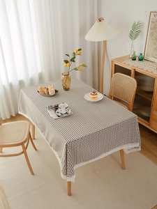 Detailed close-up of brown and white checkered tablecloth with delicate white lace edges