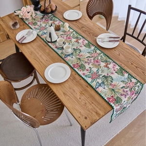 Floral tropical leaf table runner with hibiscus and monstera prints on a wooden table