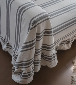 Close-up of striped cotton sofa cover featuring elegant ruffled edges and soft texture