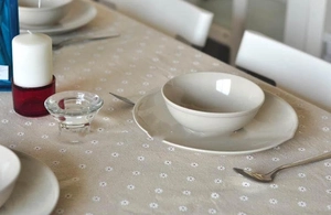 Detailed texture of beige linen tablecloth featuring white floral daisy print patterns