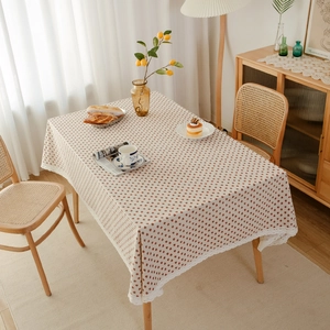 Close-up of rectangular linen tablecloth with red strawberry pattern and white lace edge