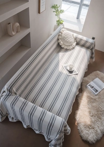 Close-up of beige cotton sofa cover with dark grey stripes and soft draped edge detail