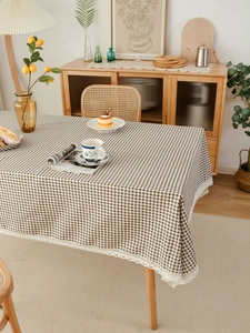 Close-up of brown gingham tablecloth with white floral lace trim and cotton linen texture