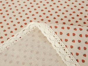 Detailed macro of strawberry print cotton linen fabric with delicate white crochet lace trim