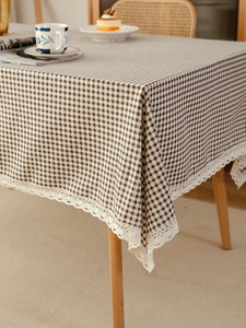 Detailed view of brown checkered tablecloth featuring white lace edges on wood table