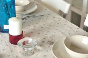 Detailed view of linen tablecloth with daisy floral prints on a cozy dining table setup