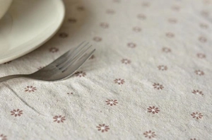 Detailed macro view of cream cotton linen fabric with a delicate daisy floral pattern