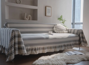 Detail of grey striped cotton sofa cover featuring elegant ruffled hem and woven texture