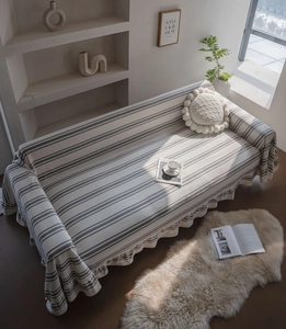 Detail of grey striped sofa cover featuring elegant ruffled edges and premium woven texture
