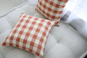 Close-up of orange and white checkered pillow covers with high-quality linen texture
