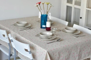 Detailed close-up of beige linen tablecloth featuring pink floral print and lace edges
