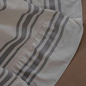 Detail of off-white striped cotton sofa cover with textured fabric and ruffled edges
