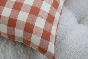 Close-up of orange and white plaid cushion cover texture on a grey fabric sofa