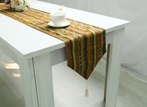 Detailed close-up of ethnic style cotton linen table runner with tassels on white wood