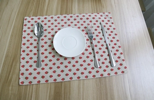 Close-up of strawberry print placemat with white plate and stainless steel cutlery set