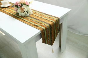 Close-up of ethnic cotton linen table runner with green stripes and tassels on white table