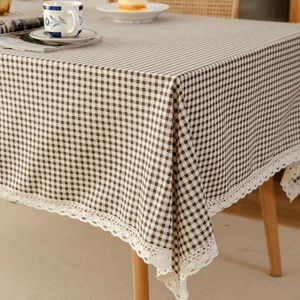 Brown and white checkered tablecloth with lace edges on a wooden dining table