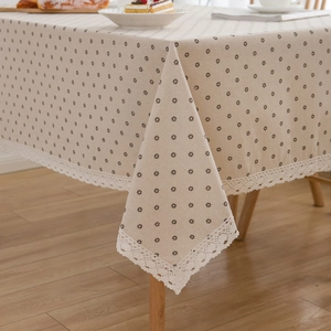 Linen cotton tablecloth with daisy print and lace edges on a wooden dining table