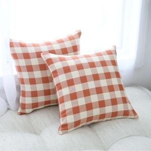 Set of 2 modern Nordic orange and white gingham check decorative pillow covers on a white sofa