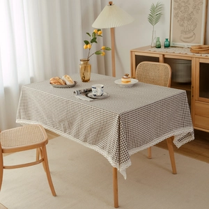 Minimalist brown and beige checkered tablecloth with white wavy lace trim in a cozy home setting
