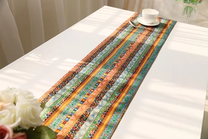 Detail of colorful bohemian woven table runner with geometric patterns on a white table